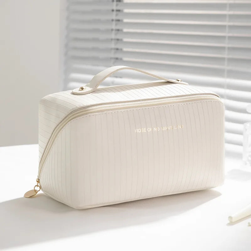 Elegante borsa cosmetica bianca con cerniera dorata, design a righe, manico superiore. Ideale per viaggi, organizzazione trucco, accessori beauty.