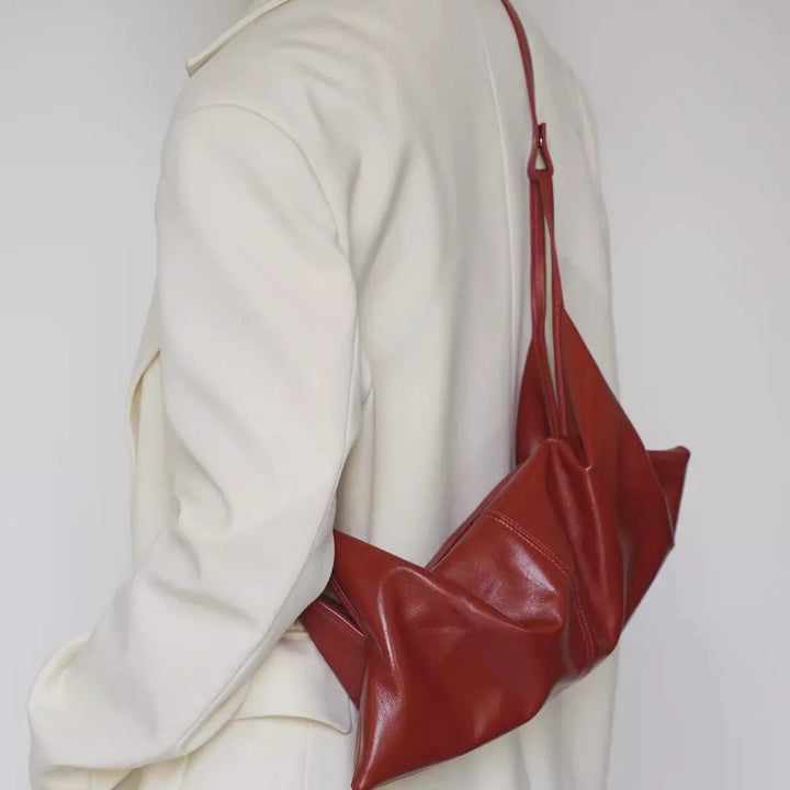 Borsa a tracolla in pelle rossa su cappotto bianco, design moderno ed elegante. Accessorio moda donna, stile contemporaneo, alta qualità.
