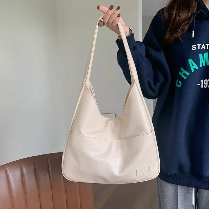 Borsa a spalla in pelle beige, design minimalista, indossata da una persona. Accessorio moda donna, elegante e versatile per ogni occasione.