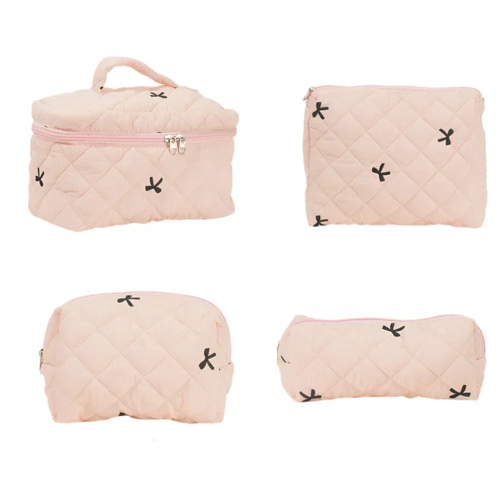 Set di quattro borse da viaggio trapuntate rosa, con cerniera e motivi a croce neri. Ideali per cosmetici e accessori. Eleganti e pratiche.