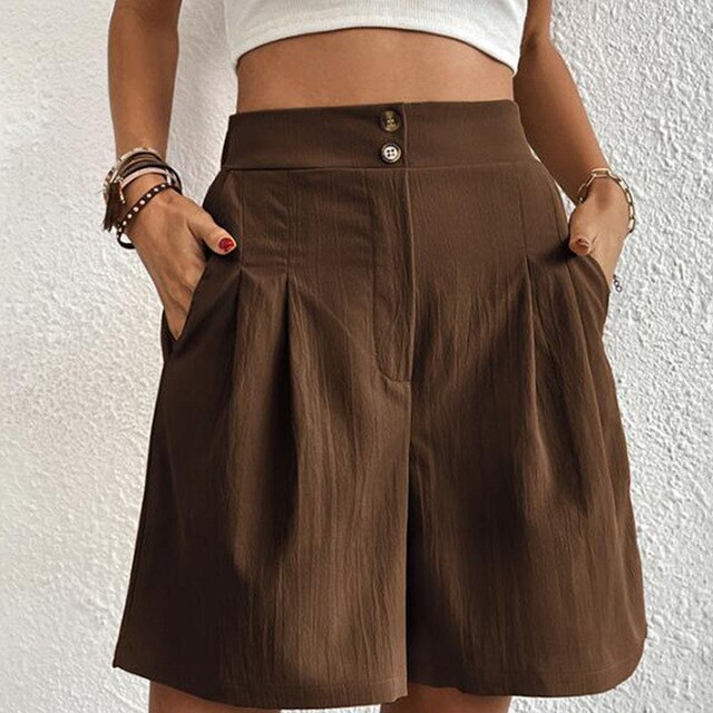 Pantaloncini marroni a vita alta, stile casual, con tasche laterali e pieghe, indossati da una donna. Ideali per moda estiva e look rilassato.