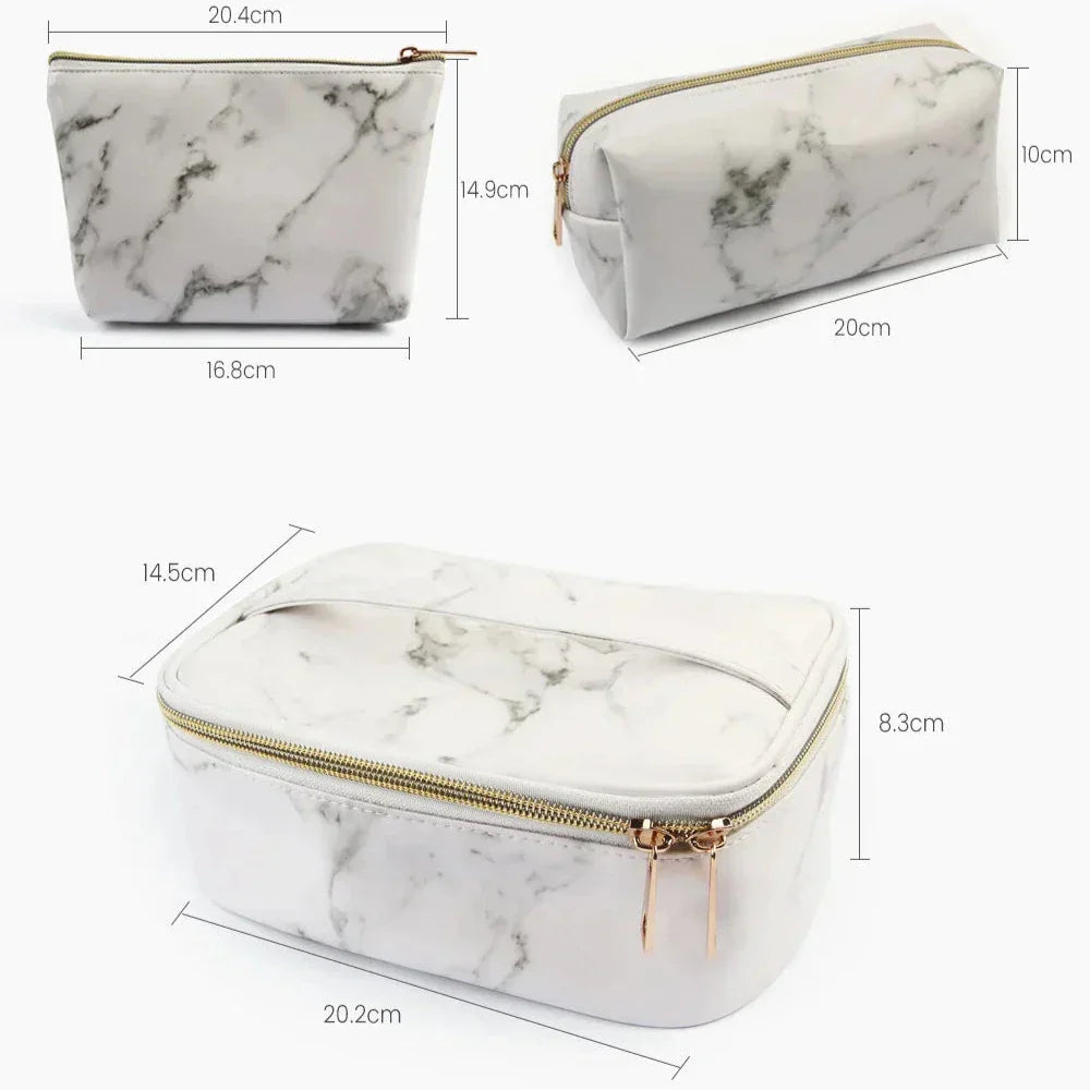 Set di tre beauty case in ecopelle effetto marmo bianco, con cerniera dorata. Dimensioni: 20x10x14 cm, 20x8.3x14.5 cm, 16.8x14.9x20.4 cm.