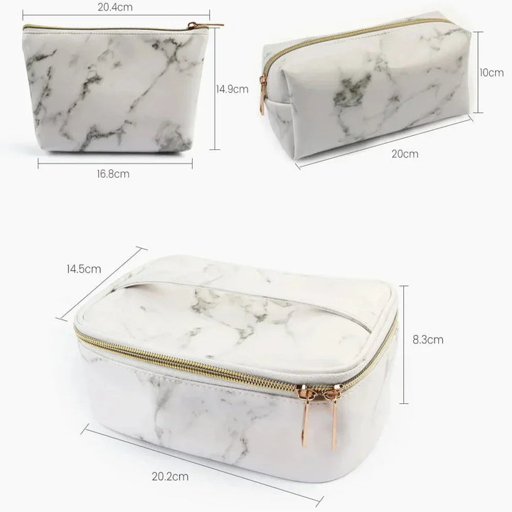 Set di tre beauty case in ecopelle effetto marmo bianco, con cerniera dorata. Dimensioni: 20x10x14 cm, 20x8.3x14.5 cm, 16.8x14.9x20.4 cm.