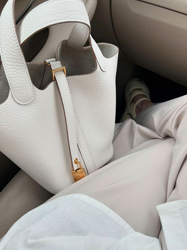 Borsa a mano in pelle bianca con dettagli dorati su sedile auto, moda elegante, accessori di lusso, stile minimalista, outfit estivo.