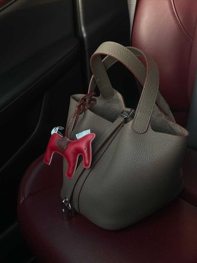Borsa a secchiello in pelle marrone su sedile auto, con ciondolo a forma di cavallo rosso. Accessorio moda elegante, design moderno.