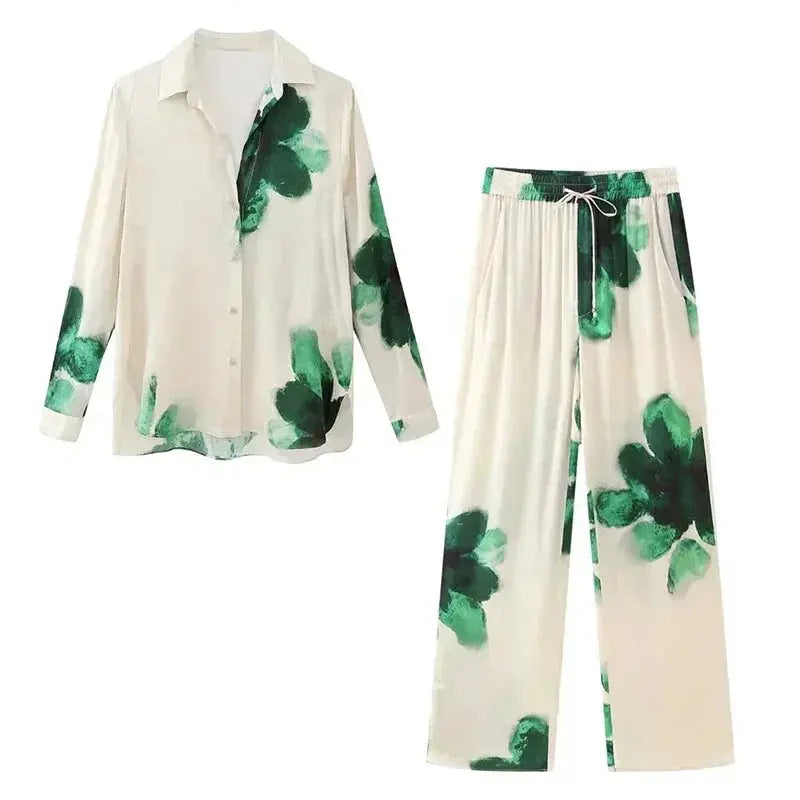 Completo pigiama donna in raso, fantasia floreale verde su sfondo bianco, camicia a maniche lunghe e pantaloni larghi, moda notte elegante.