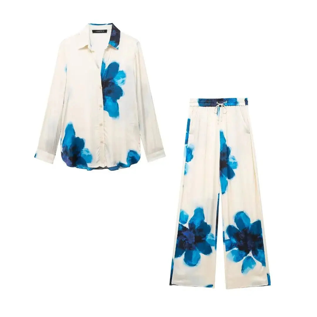 Completo pigiama donna in seta bianca con stampa floreale blu, camicia a maniche lunghe e pantaloni larghi. Elegante e confortevole.