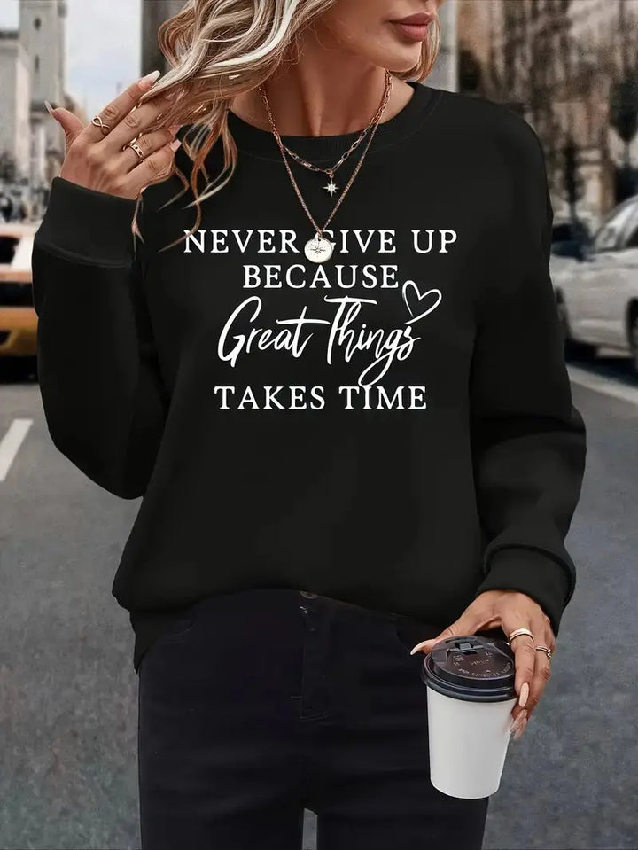 Donna con felpa nera con scritta motivazionale, collane dorate e caffè in mano. Moda casual autunnale, abbigliamento street style.