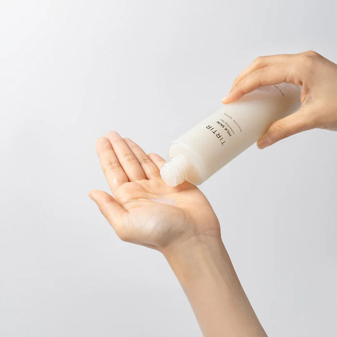 Mani versano tonico viso idratante incolore da flacone bianco su sfondo neutro. Cura della pelle, cosmetici, routine bellezza.