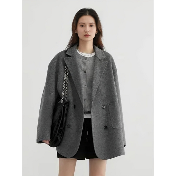 Giacca donna grigia oversize, elegante e moderna, con bottoni neri. Indossata con borsa a catena e abbigliamento casual. Moda autunno inverno.