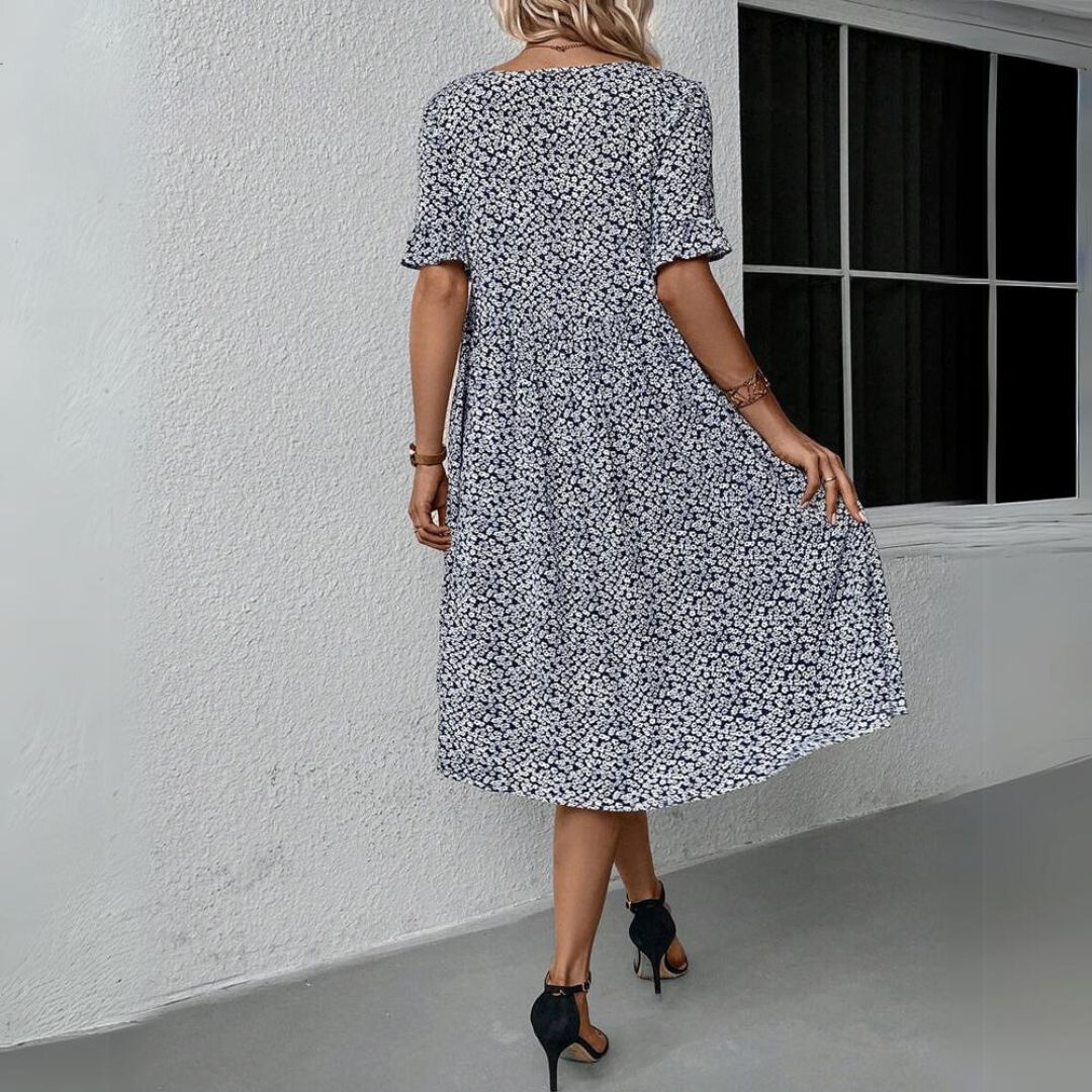 Abito estivo donna floreale blu e bianco, maniche corte, lunghezza al ginocchio, indossato con tacchi neri. Elegante e casual per ogni occasione.