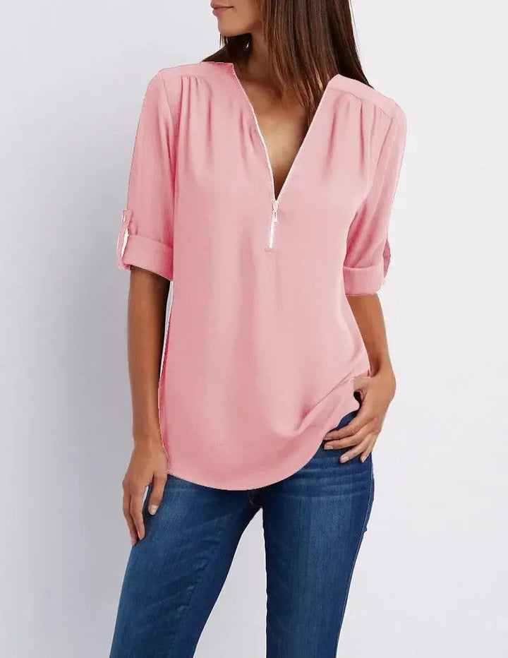 Donna con camicia rosa a maniche lunghe e zip, abbinata a jeans blu. Moda casual femminile, abbigliamento primaverile, stile elegante.