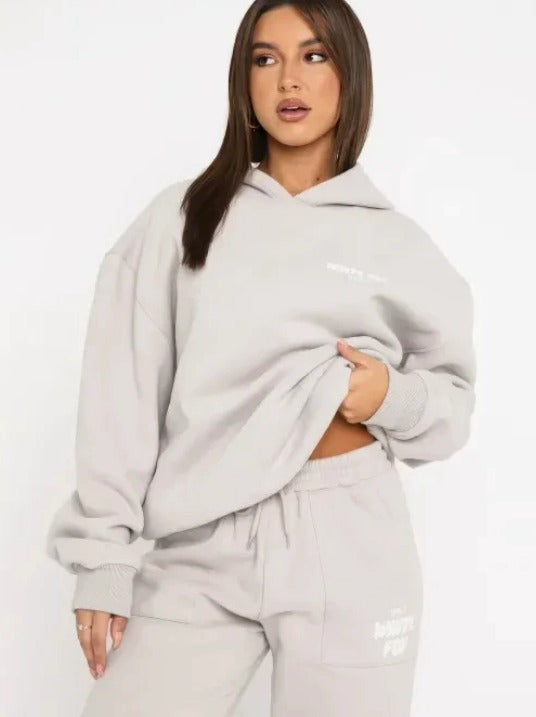 Donna con felpa oversize grigia e pantaloni coordinati, moda casual autunno, abbigliamento comodo, stile streetwear, tendenza 2023.