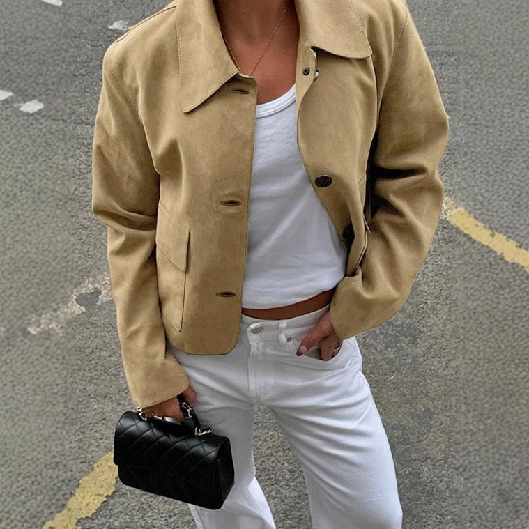 Giacca beige su donna con top bianco e pantaloni bianchi, borsa nera trapuntata. Moda casual chic, abbigliamento autunnale elegante.