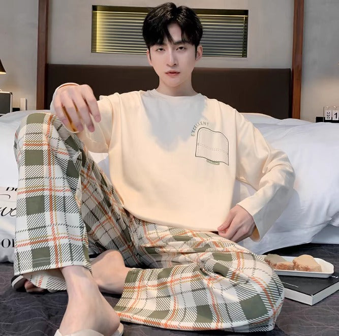 Giovane uomo in pigiama plaid verde e bianco, seduto su letto moderno. Moda uomo, abbigliamento notte, comfort, stile casual.