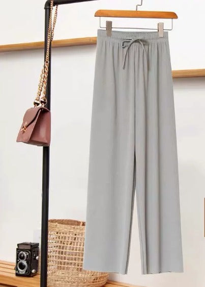 Pantaloni grigi larghi appesi su appendiabiti, accanto a borsa a tracolla marrone e fotocamera vintage. Moda casual, abbigliamento donna elegante.