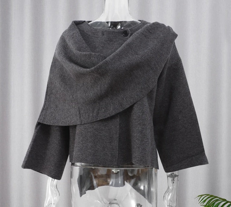 Cappotto grigio scuro in lana, design asimmetrico, maniche a tre quarti, su manichino trasparente. Moda autunno inverno, abbigliamento elegante.