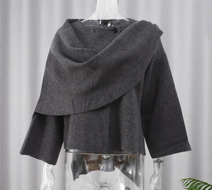 Cappotto grigio scuro in lana, design asimmetrico, maniche a tre quarti, su manichino trasparente. Moda autunno inverno, abbigliamento elegante.