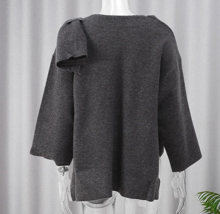 Maglione oversize grigio scuro in lana, maniche lunghe, design asimmetrico, sfondo neutro, moda autunno inverno, abbigliamento casual elegante.