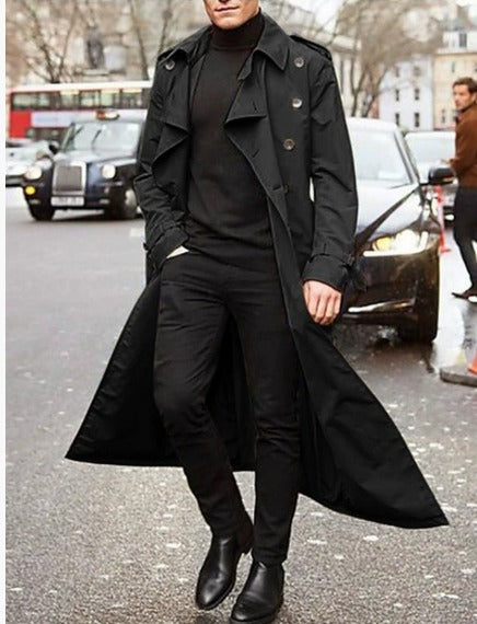 Uomo in cappotto nero lungo, maglione e pantaloni neri, stivali eleganti, cammina in città. Moda maschile, stile urbano, abbigliamento invernale.