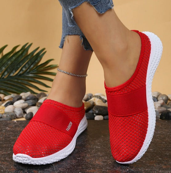 Scarpe da ginnastica rosse da donna, tessuto traspirante, suola bianca antiscivolo, indossate con jeans strappati. Calzature moda casual estive.