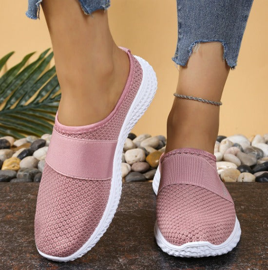 Scarpe da ginnastica rosa in tessuto traspirante, suola bianca, indossate con jeans strappati. Scarpe casual donna, moda comoda, stile estivo.