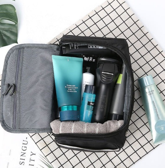 Beauty case aperto con prodotti per la cura della pelle e rasatura su sfondo a quadretti. Include creme, lozioni e rasoio elettrico.