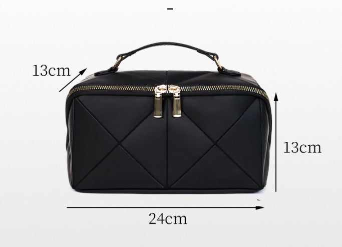 Borsa da viaggio nera in pelle con cerniera dorata, manico superiore, design trapuntato, dimensioni 24x13x13 cm. Elegante e compatta.