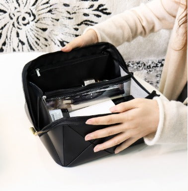 Donna apre borsa cosmetica nera con scomparti, contenente trucchi e accessori. Design elegante, ideale per organizzare prodotti di bellezza.