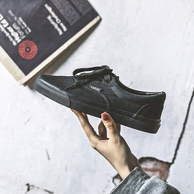 Scarpa da ginnastica nera in mano, design casual, suola in gomma, sfondo grigio. Scarpe moda uomo, calzature sportive, stile urbano.