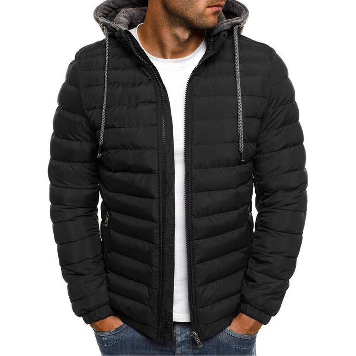 Giacca invernale nera imbottita da uomo con cappuccio, indossata sopra una maglietta bianca e jeans. Stile casual, moda maschile autunno inverno.
