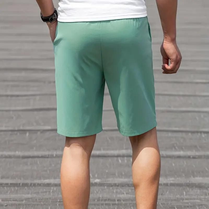 Pantaloncini sportivi verdi da uomo, tessuto leggero, indossati all'aperto. Ideali per attività fisica e tempo libero.