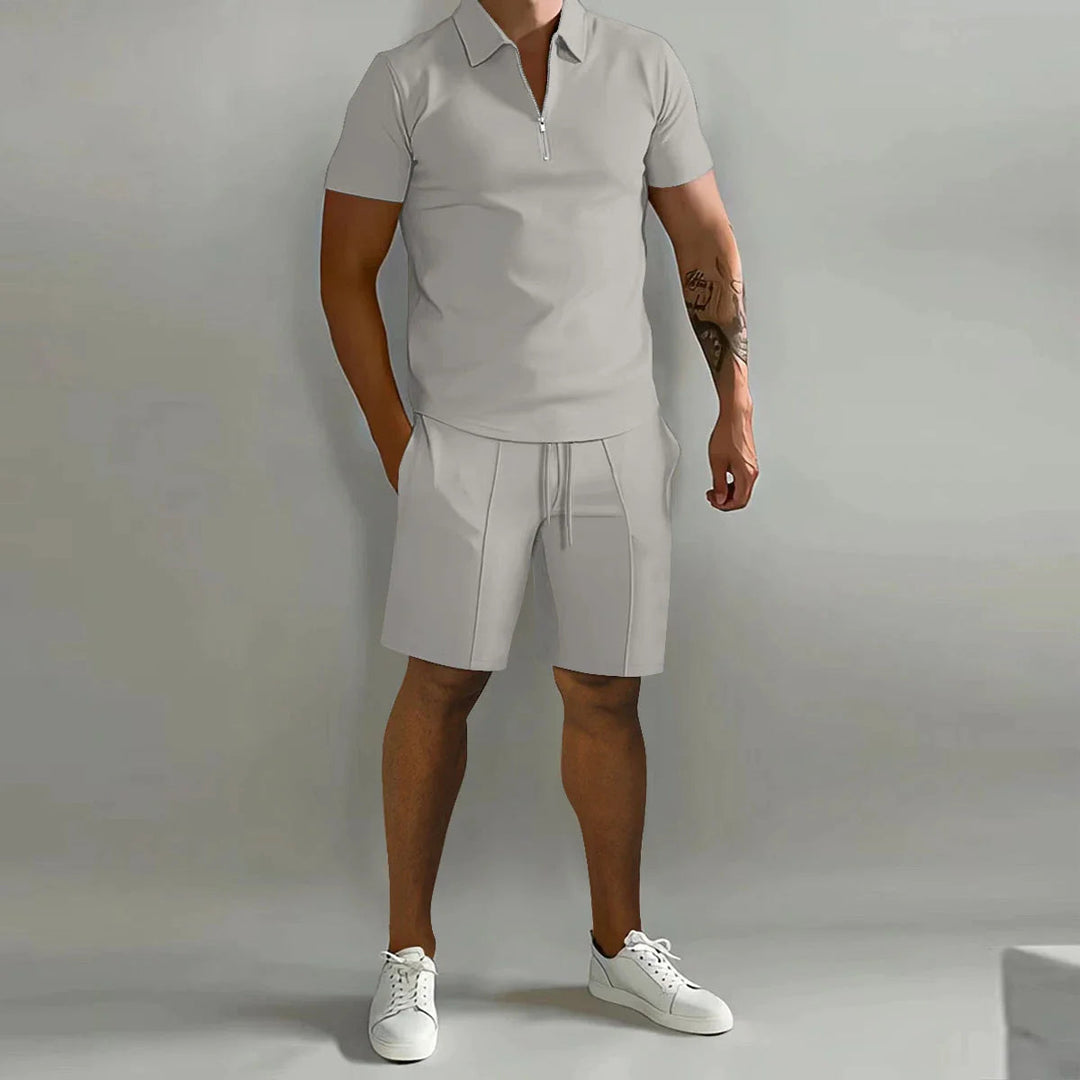 Uomo in completo estivo casual grigio, polo con zip e pantaloncini, scarpe da ginnastica bianche. Moda maschile, abbigliamento estivo elegante.