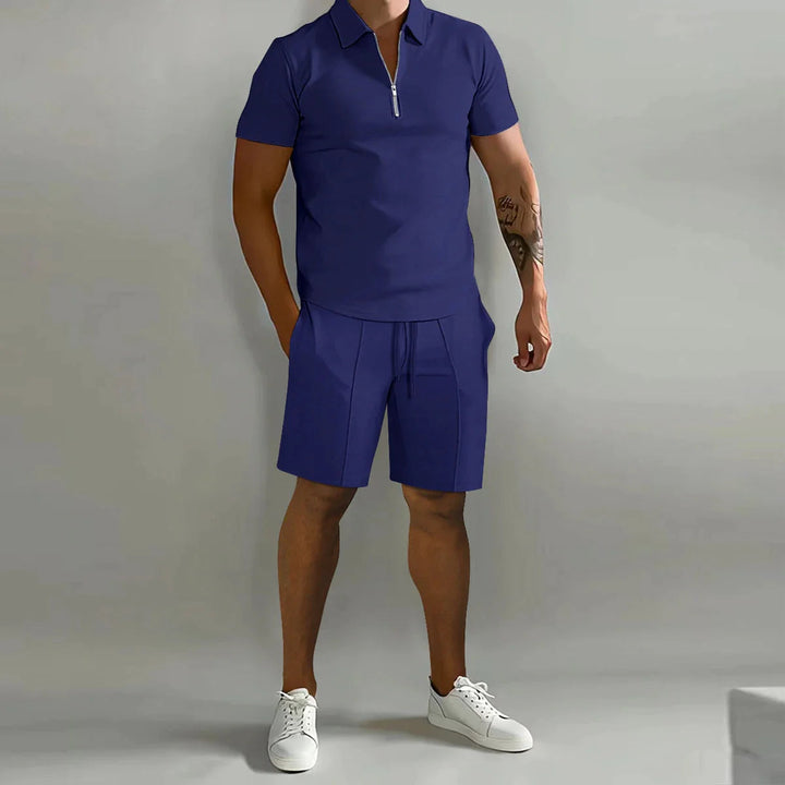 Uomo in completo estivo blu navy con polo a zip e pantaloncini, scarpe bianche. Moda casual maschile, abbigliamento estivo elegante.