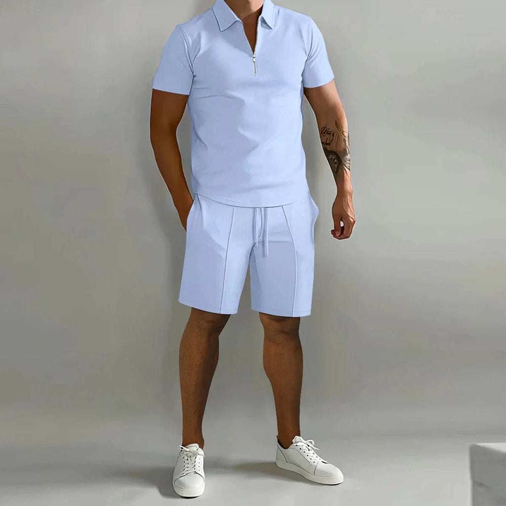 Uomo in completo estivo casual azzurro, polo con zip e pantaloncini, scarpe da ginnastica bianche. Moda maschile estiva, abbigliamento casual elegante.