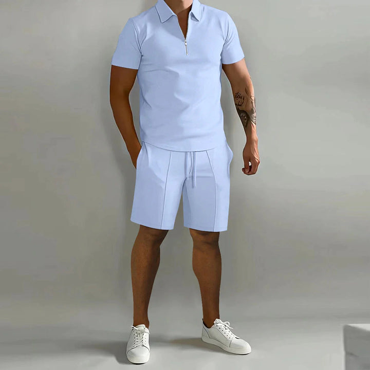 Uomo in completo estivo casual azzurro, polo con zip e pantaloncini, scarpe da ginnastica bianche. Moda maschile estiva, abbigliamento casual elegante.