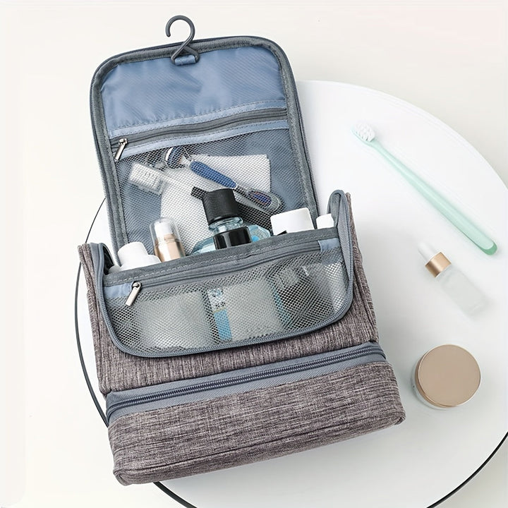 Beauty case da viaggio grigio aperto con gancio, contenente articoli da toeletta come spazzolino, flaconi e rasoio. Organizzatore cosmetici.