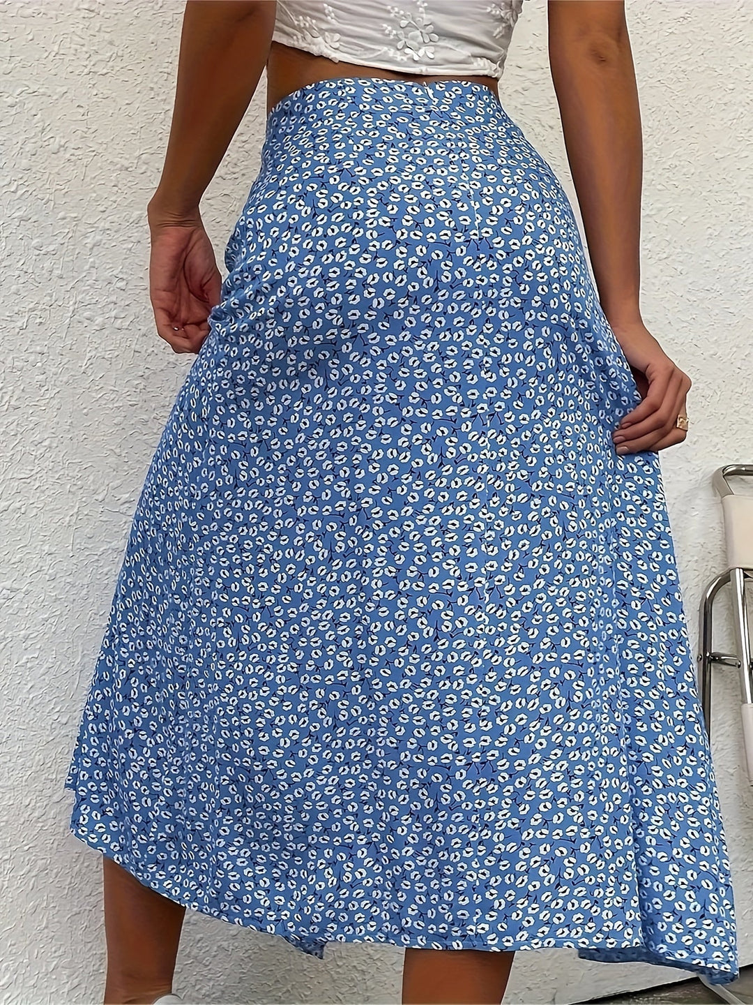 Gonna lunga blu a fiori bianchi, indossata da una donna, su sfondo bianco. Moda estiva, abbigliamento femminile elegante e casual.
