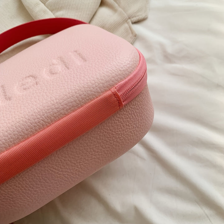 Borsa a tracolla rosa in pelle con cerniera rossa su sfondo bianco. Design elegante e moderno, ideale per moda femminile e accessori di tendenza.