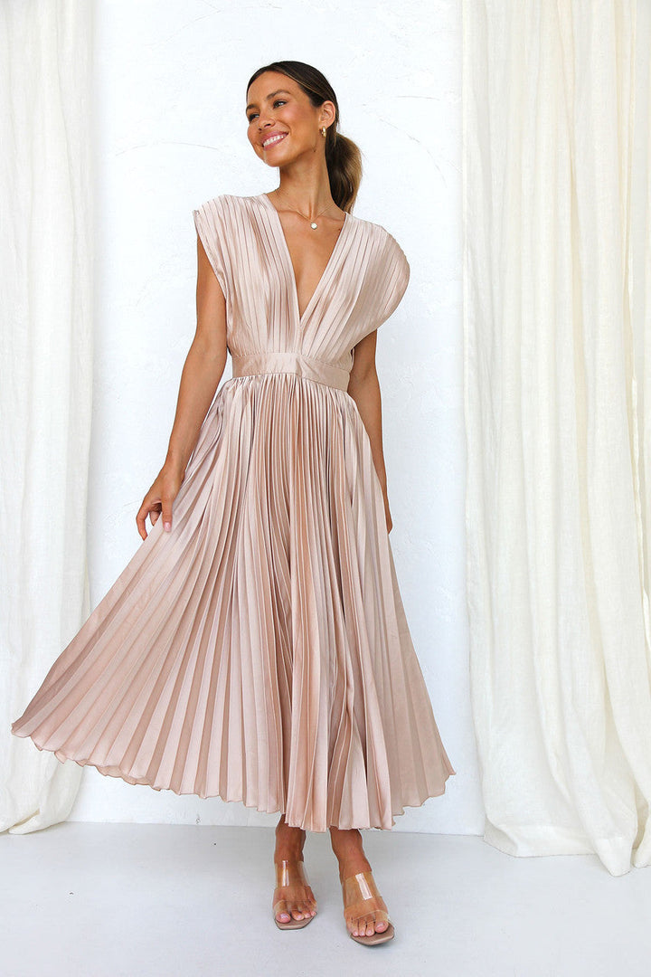 Abito lungo plissettato color champagne, scollatura a V profonda, indossato da donna sorridente. Elegante moda femminile, abbigliamento estivo.