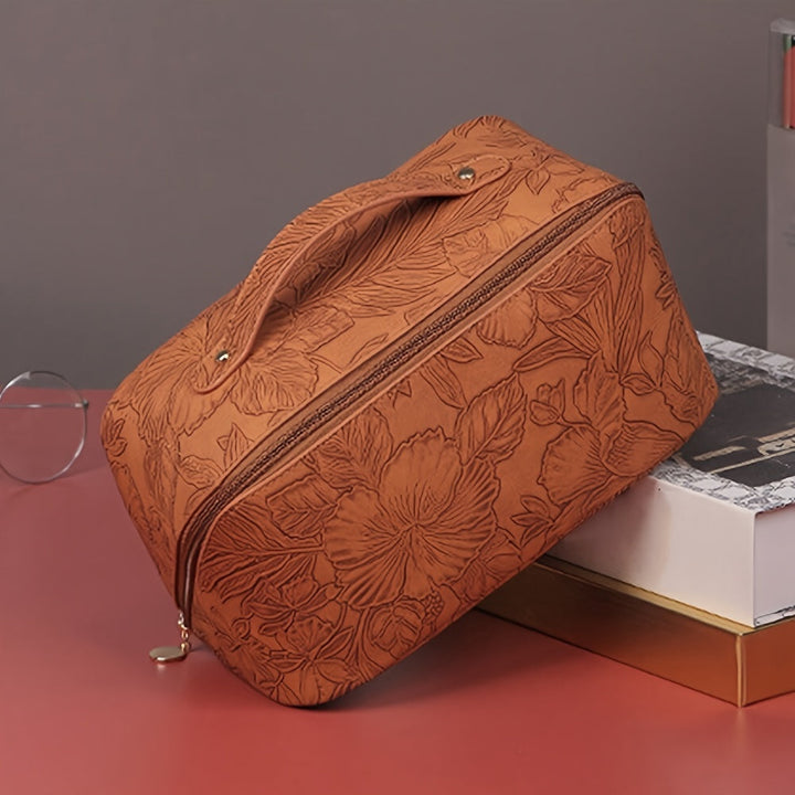 Borsa da trucco in pelle marrone con motivo floreale, chiusura a zip, manico superiore. Elegante e pratica per organizzare cosmetici.