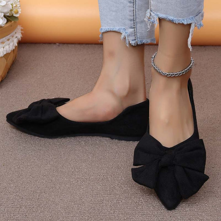 Scarpe ballerine nere con fiocco, indossate con jeans strappati. Eleganti e alla moda, ideali per look casual e chic. Accessorio cavigliera argento.