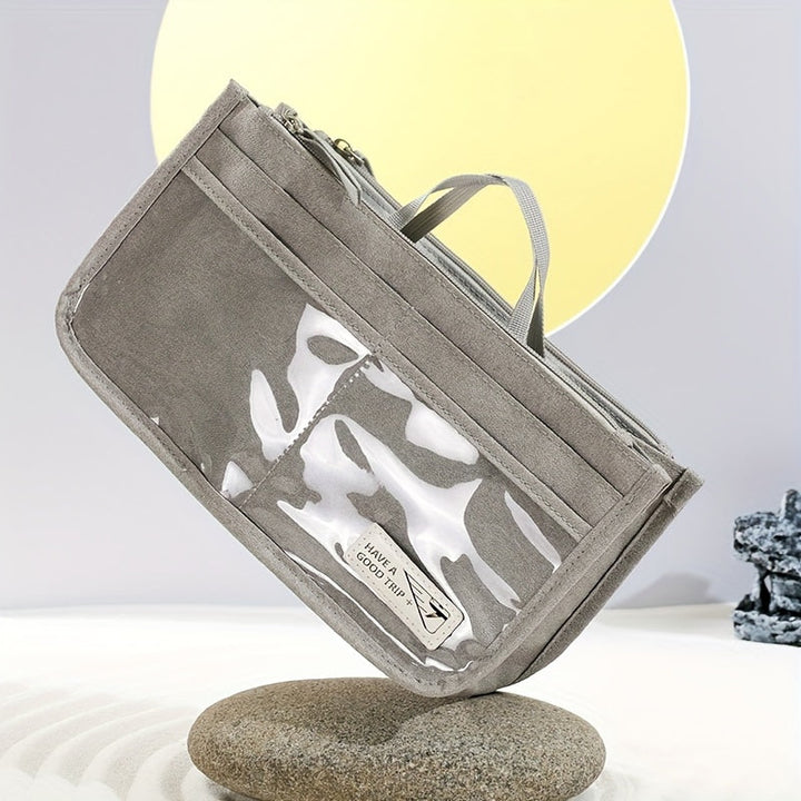 Astuccio grigio in tessuto con manico, tasca trasparente e chiusura a zip, posizionato su pietra. Design moderno, ideale per scuola o ufficio.