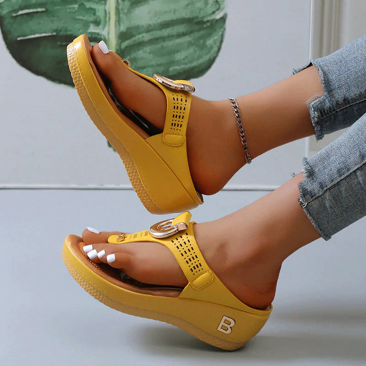 Sandali gialli da donna con zeppa, cinturino regolabile e logo, indossati con jeans. Scarpe estive moda, comode e trendy.