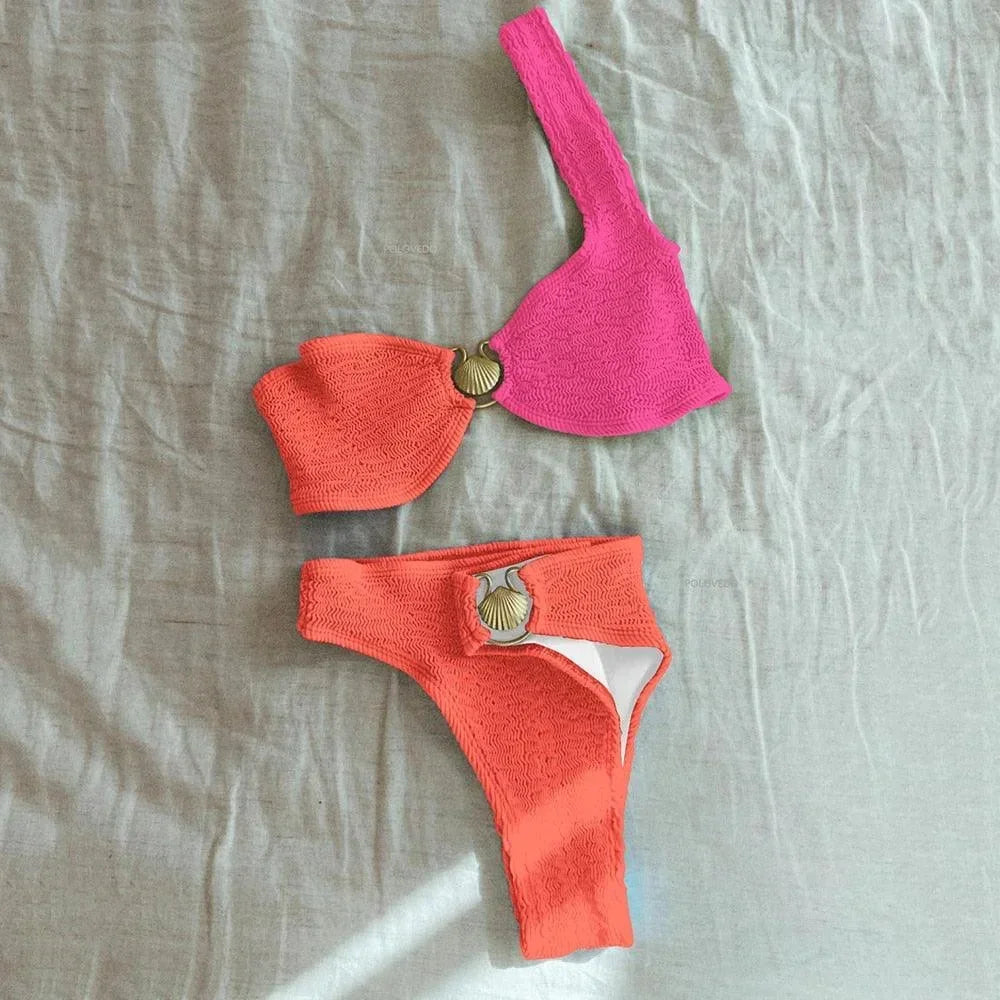 Bikini asymétrique en tissu texturé, avec un anneau décoratif, offrant un style moderne et confortable pour la plage.