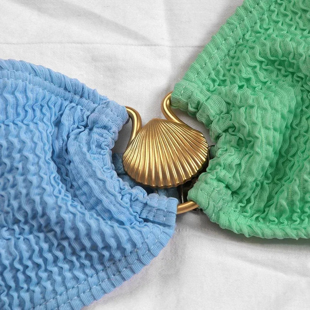 Bikini asymétrique féminin en tissu texturé, avec anneau décoratif au niveau du décolleté et taille échancrée.