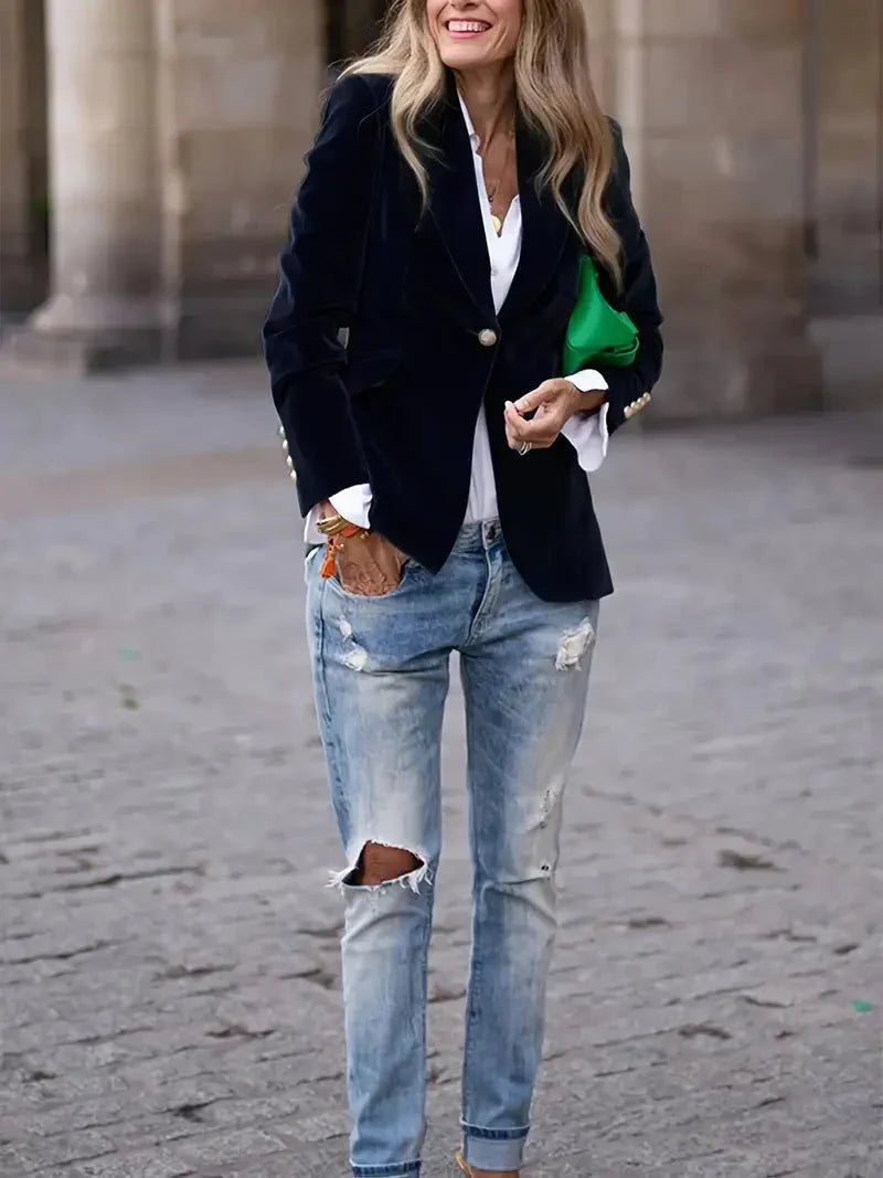 Blazer ajusté en velours noir pour femme, avec boutons décoratifs modernes et coupe cintrée.
