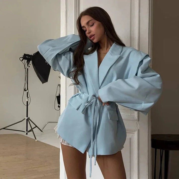 Blazer femme bleu à laçage, avec épaulettes, coupe moderne et design soigné.
