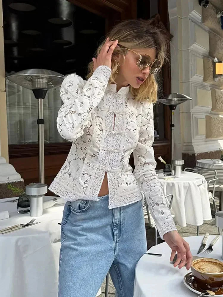 Blouse en dentelle blanche à col montant et manches longues, avec des détails délicats et une coupe féminine.