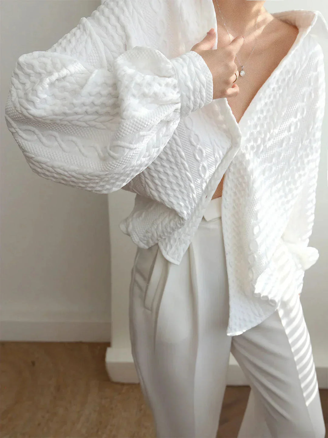Blouse femme blanche en tissu texturé, avec manches sculptées, offrant un style unique et une coupe confortable.